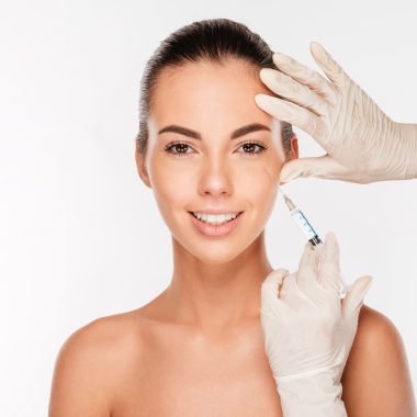 Young woman gets beauty injection in eye area from sergeant Beautiful young woman gets beauty injection in eye area from sergeant isolated on white background